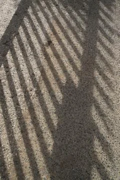 Deep shadow of some thick railings cast across the floor by the sun. Stock Photos