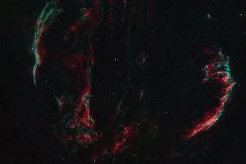 A deep space image shows the red and green gas filaments of a nebula Stock Photos