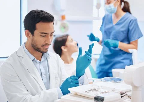 Deep in through during the selection process. Shot of a dentist applying his Stock Photos