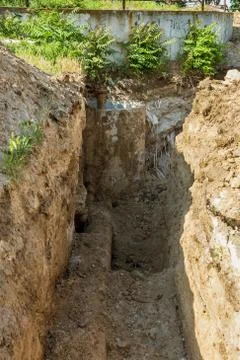 Deep trench with old rusty iron water pipes, prepared for dismantling of worn Stock Photos