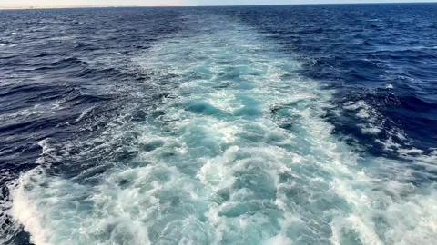 Deep turquoise ship wake cuts through indigo Mediterranean waters on a bright Stock Footage 332481432