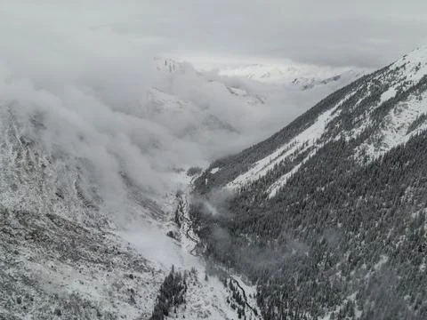 Deep winter mountain canyon surrounded by low clouds Stock Photos