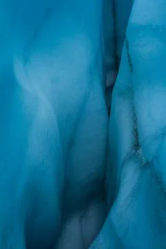 Deep within an ice cave looking in with deep blue color to the curvy ice wall Stock Photos