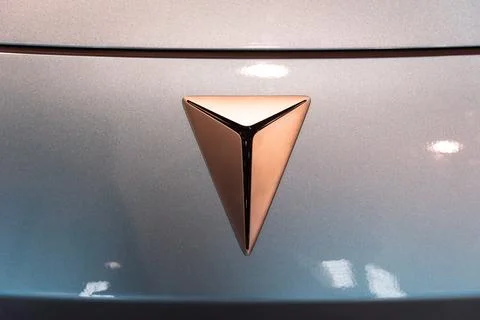 Deepal EV copper triangle logo close-up on light blue metallic body at ECAR.. Stock Photos