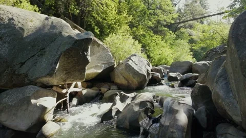 Deer creek rapids over large boulders with a hiking bridge Stock Footage 301020212