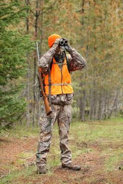 Deer hunter looking through binoculars Stock Photos