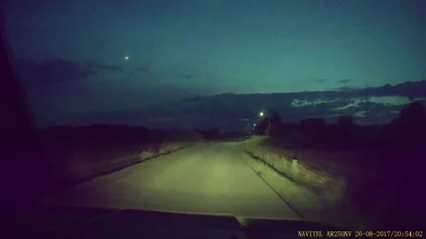 A deer jumping in front of the hood of a car driving on a suburban road at night Stock Footage 277422155