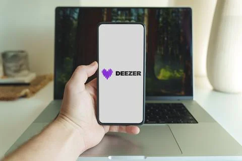 Deezer music streaming application logo on smartphone screen in front of laptop Stock Photos