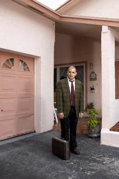 A defeated looking businessman standing in his driveway Stock Photos