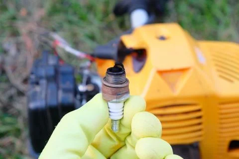 Defective spark plug on the background of a grass trimmer Fotos de archivo