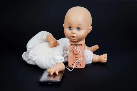 Defective talking doll with his hand on a mobile phone Stock Photos