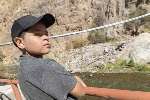 Defiant kid with cup looking at the camera with river and mountains 스톡 사진