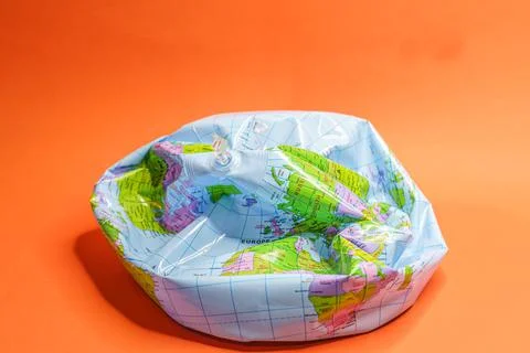 Deflated globe isolated on orange background. Stock Photos