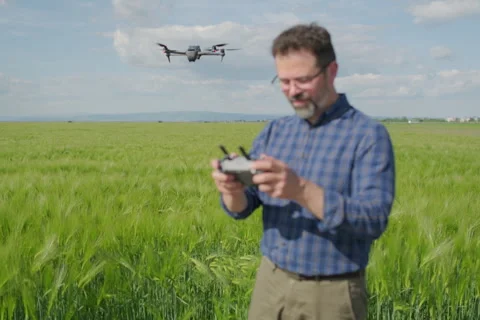 Defocalized agronomist piloting drone checking green barley crop Stock Footage 337249155