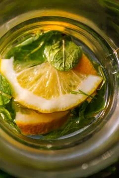 Defocus close-up slice lemon and leaves of mint in glass jug of lemonade natu Stock Photos