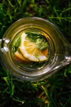 Defocus close-up slice lemon and leaves of mint in glass jug of lemonade natu Foto stock