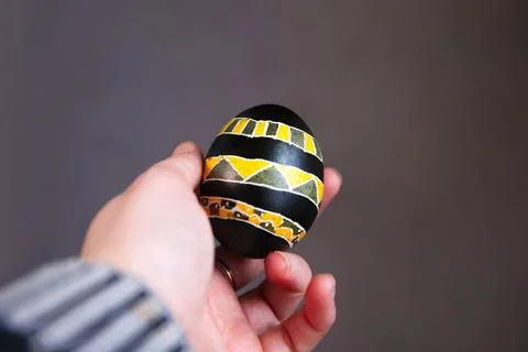 Defocus Easter black and yellow egg in female hand. Close up Easter eggs pa.. Stock Photos