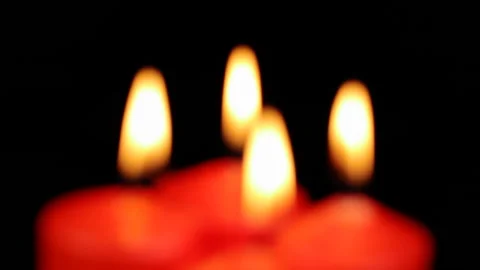 In defocus, four red candles are burning slowly spinning on a black background Видео 144267684