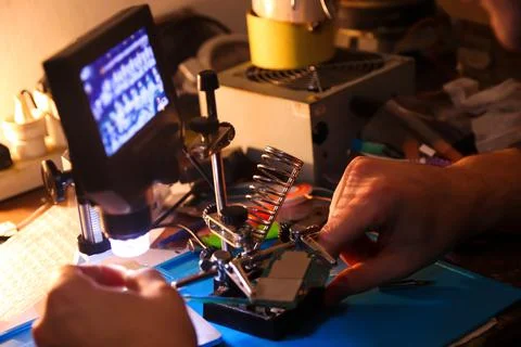 Defocus male hand with microscope. Work with a soldering iron. Microelectroni Фото