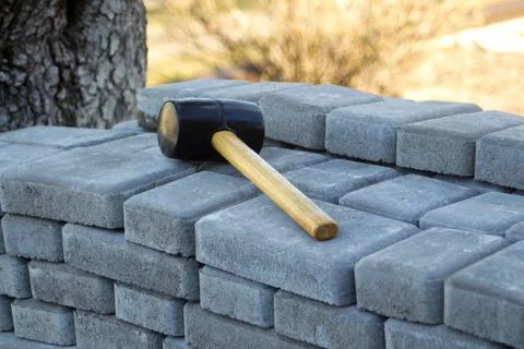 Defocus paving hammer. Stack of paving stones. Garden brick pathway paving by Stock Photos