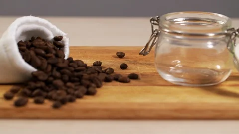 Defocus of roasted coffee beans closeup scattered on table with small jar of 4K Stock Footage 114629968