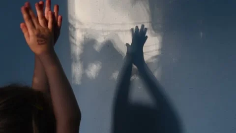 Defocus shadows of kid clapping hands on stucco wall surface with copy space Stock Footage 138297221