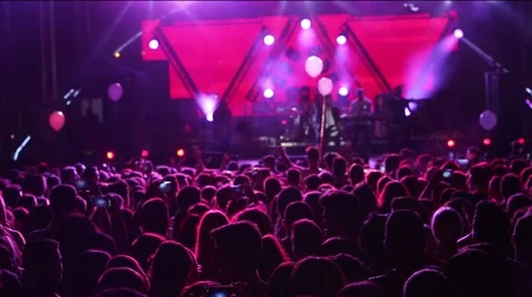 Defocus silhouettes of concert crowd in front of bright stage lights Stock Footage 67515378