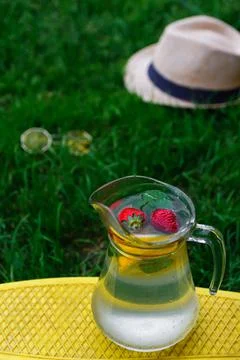 Defocus two strawberry, slice lemon and leaves of mint in glass jug of lemona Stock Photos