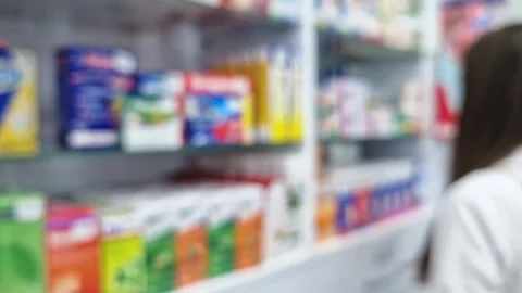 Defocus view inside of pharmacy with female pharmacist arranging drugs on the sh Stock Footage 261960535