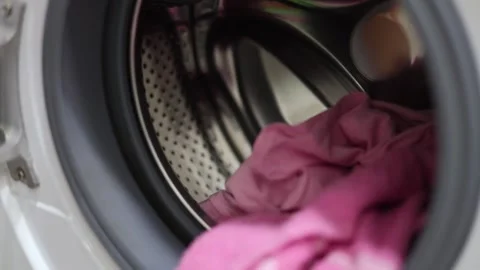 Defocused 4K video close up. 60 fps. Man puts dirty pink clothes, laundry Stock Footage 332573575