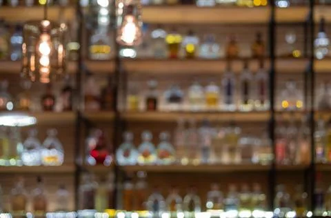 Defocused background of bar counter with various bottles of alcohol. Stock Photos