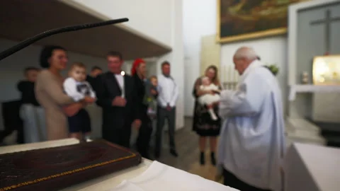 DEFOCUSED: Baptism process in a catholic church with priest and newborn's family Video stock 219901676