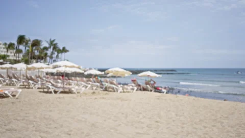 Defocused beach scene with empty chairs and parasols, palm trees, white san.. Stock Footage 297606777
