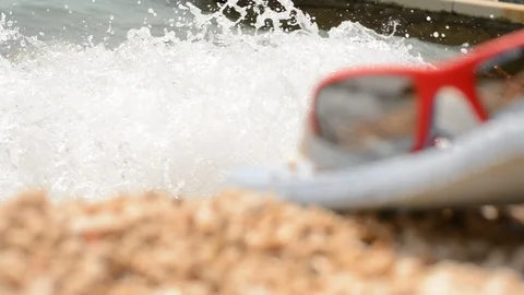Defocused blue flip-flops and red sun glasses at sea cost. Stock Footage 91803715