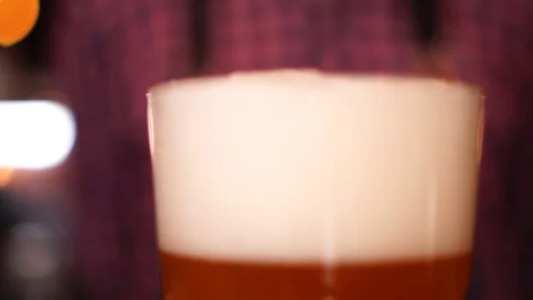 Defocused bokeh close up view on beer glass with lager pint white foam on top in Stock Footage 103745130