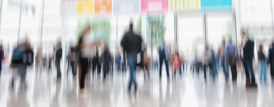 Defocused business people walking in trade show hall Stock Photos