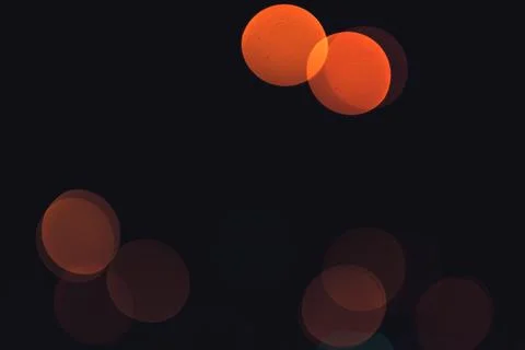 Defocused circular light spots in warm orange tones scattered across dark Stock Photos