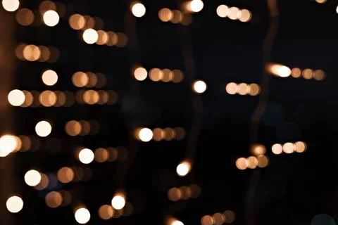 Defocused image of scattered golden string lights glowing softly against a .. Stock Photos