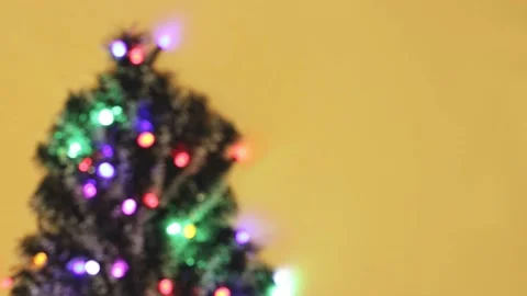 Defocused lights with different colors and christmas tree on yellow background Video stock 144495283