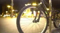 Defocused night city lights and pedestrians seen through bicycle wheel spokes 4k or 4k+ Resolution