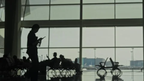 Defocused passengers silhouettes walking, sitting in waiting airport room Vídeos de archivo 119989983