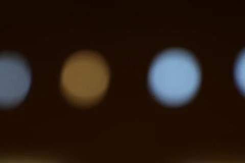 Defocused row of lights creating a bokeh effect in blue and yellow Stock Photos