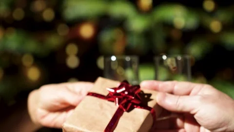 Defocused shoot of hands giving gift box with Christmas tree lights and cha.. Stock Footage 293781360