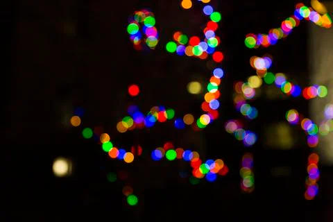 Defocused tree branches decorated with strings of christmas lights Stock Photos
