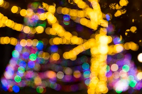 Defocused tree branches decorated with strings of multicolored christmas ligh Stock Photos