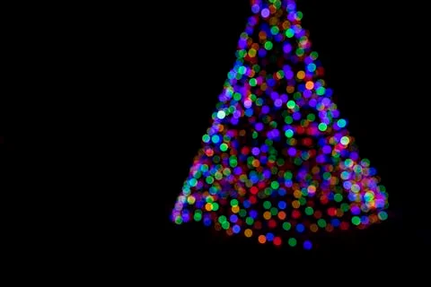 Defocused triangle shape of multicolored lights over dark background Stock Photos