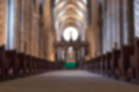 Defocused view down the aisle between pews towards the alter in cathedral Stock Photos