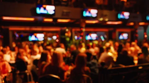 A defocused view of a lively crowd in a vibrant venue filled with TVs and Stock Footage 315958133