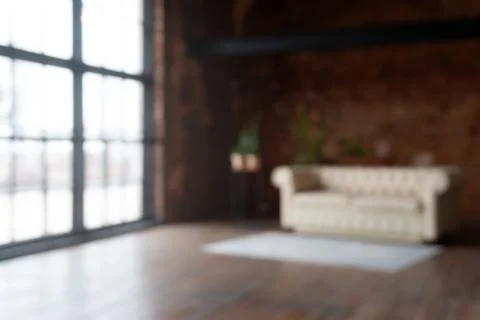 Defocused view on an open space loft interior with big windows filled with su Stock Photos