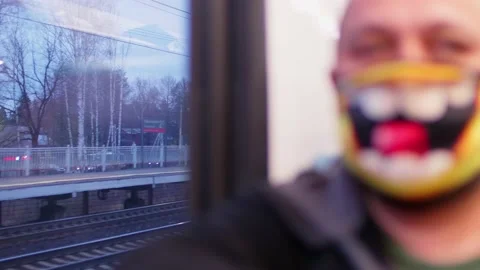 Defocused view of passanger in mask sitting ner window in wagon of train passing Stock Footage 147725903
